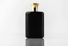 a front view black fragrance designed with gold cap on the white floor